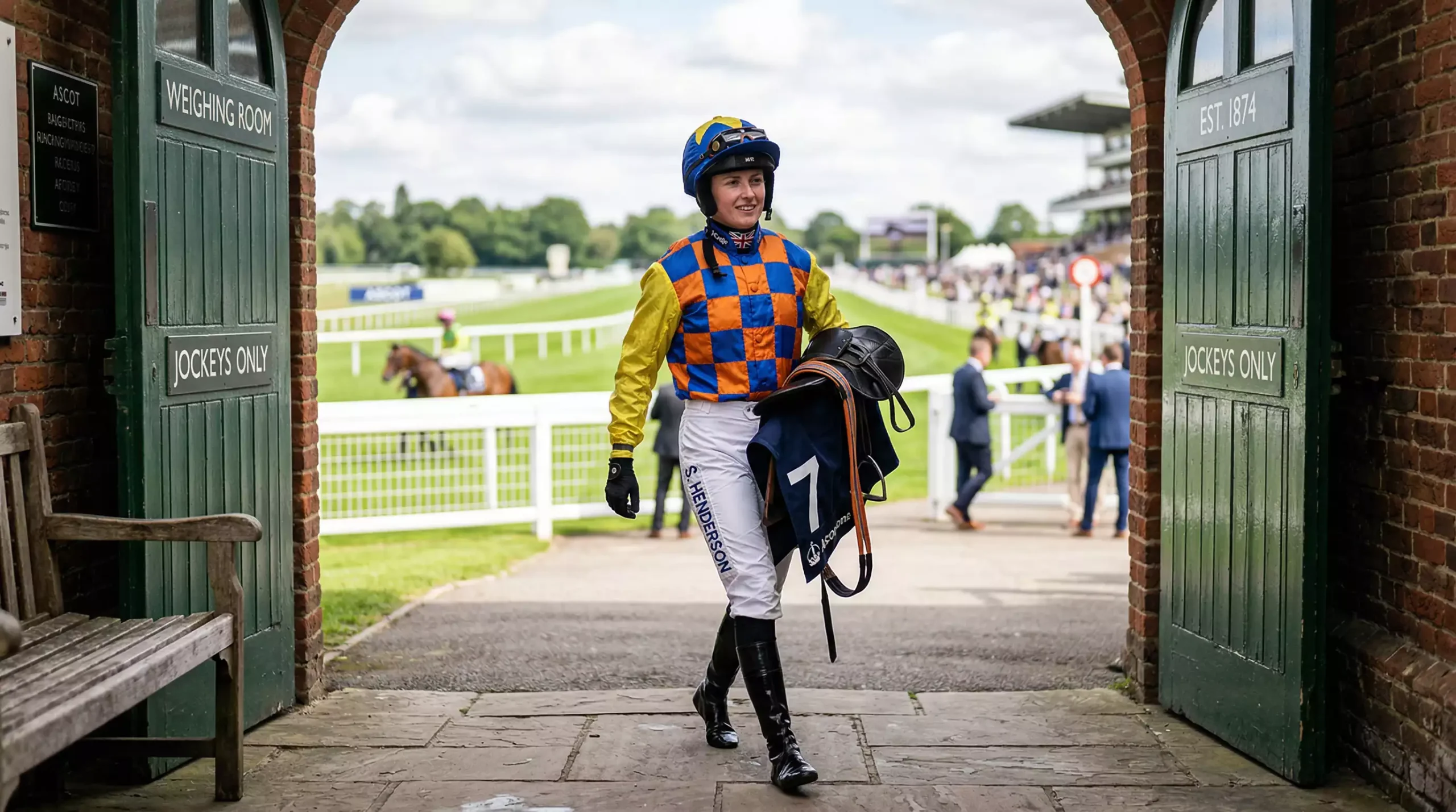 Jockey in colourful silks walking towards the weighing room at a UK racecourse